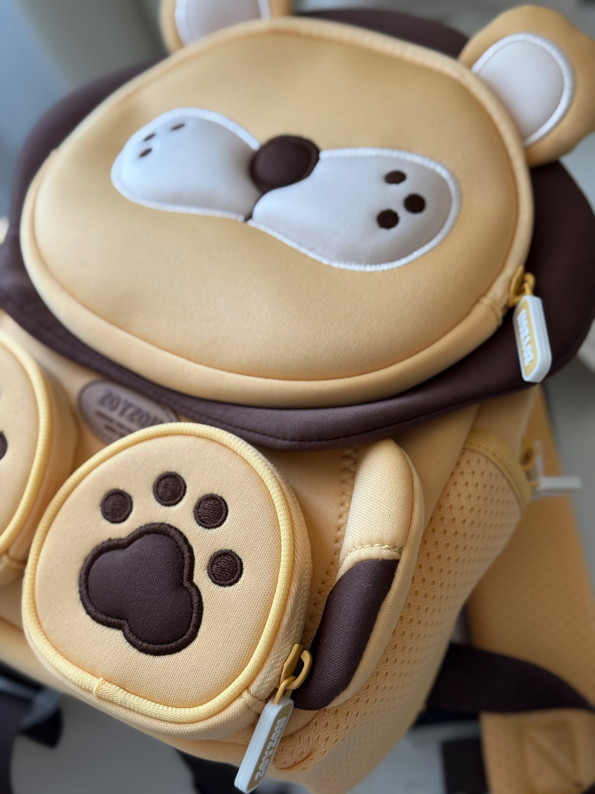 Mochila preescolar con forma de león y huellas en la parte frontal